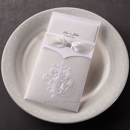 Textured trifold insert card in high rise fonts, enclosed in a delicately made pocket with embossed vintage theme detail, adorned with a silky-smooth ribbon with a jeweled center
